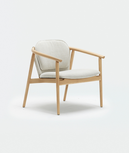 A modern accent chair with a minimalist design, featuring a light wood frame and light gray fabric upholstery on the seat and backrest. The chair has angled legs and armrests, creating a sleek and contemporary look.