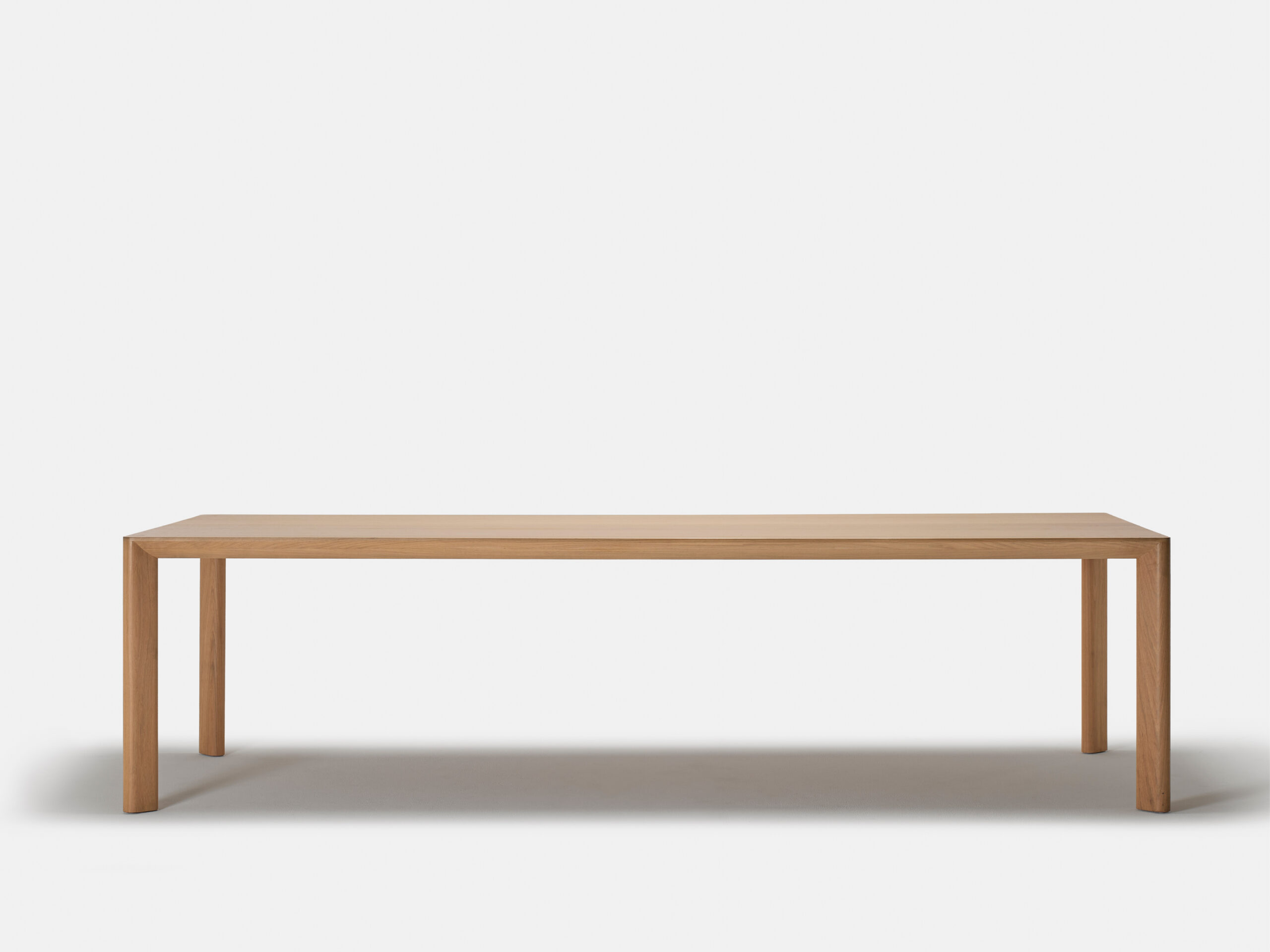 A simple wooden rectangular table with four straight legs, shown against a plain white background.
