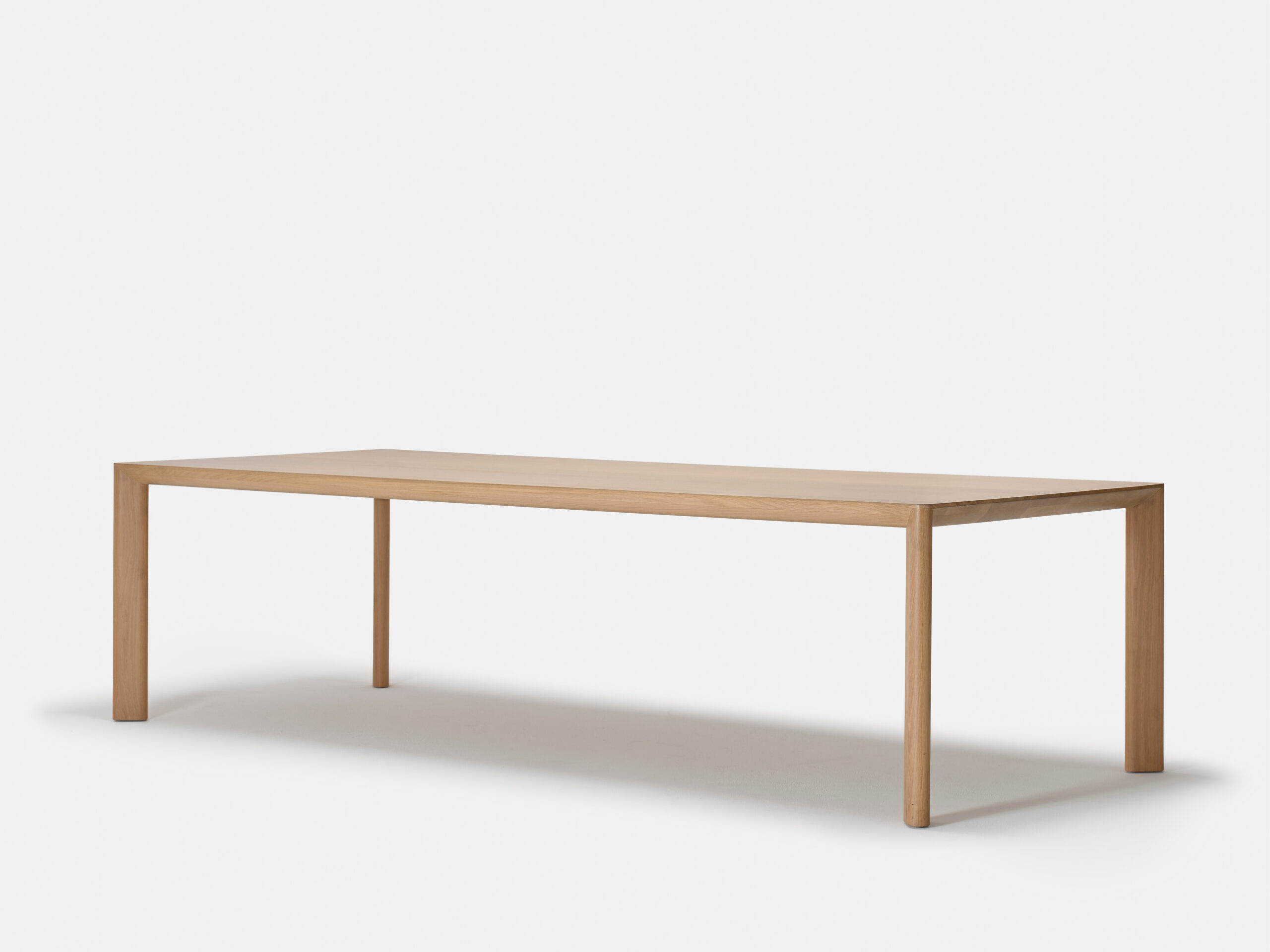 A simple, modern rectangular wooden table with four straight legs, photographed against a plain white background.