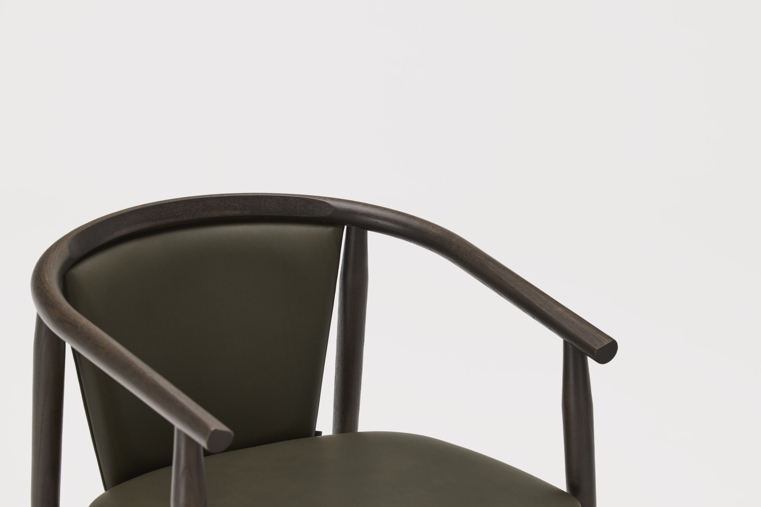 A close-up of a modern chair with a dark wooden frame, curved armrests, and an olive green leather backrest and seat, set against a plain white background.
