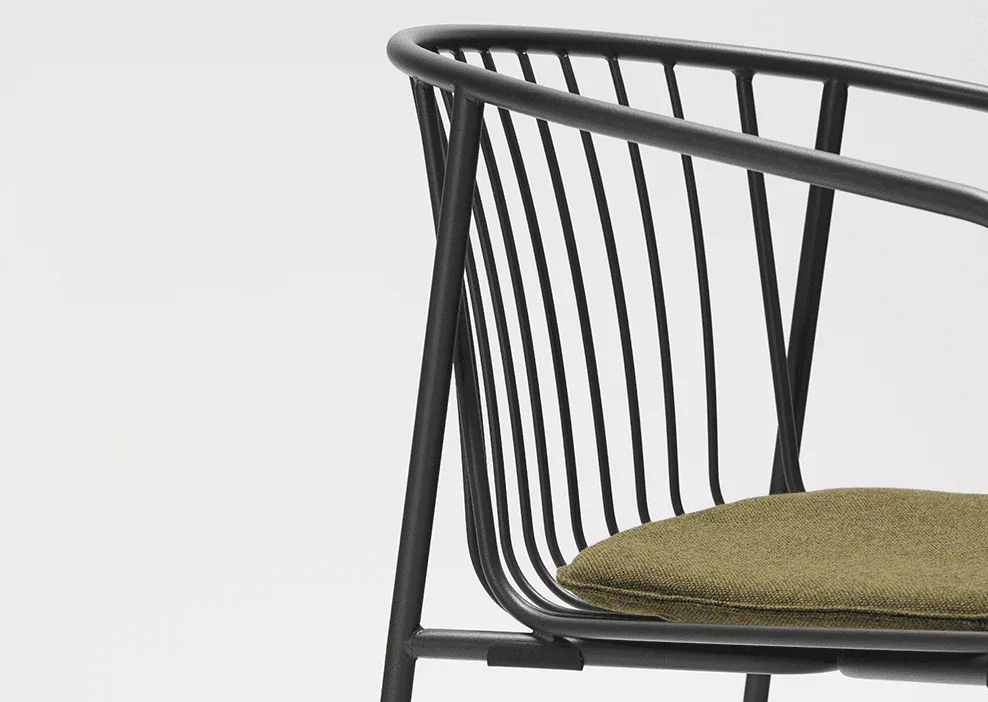 Close-up of a modern black metal chair with vertical slats and an olive green fabric seat cushion, set against a plain white background.