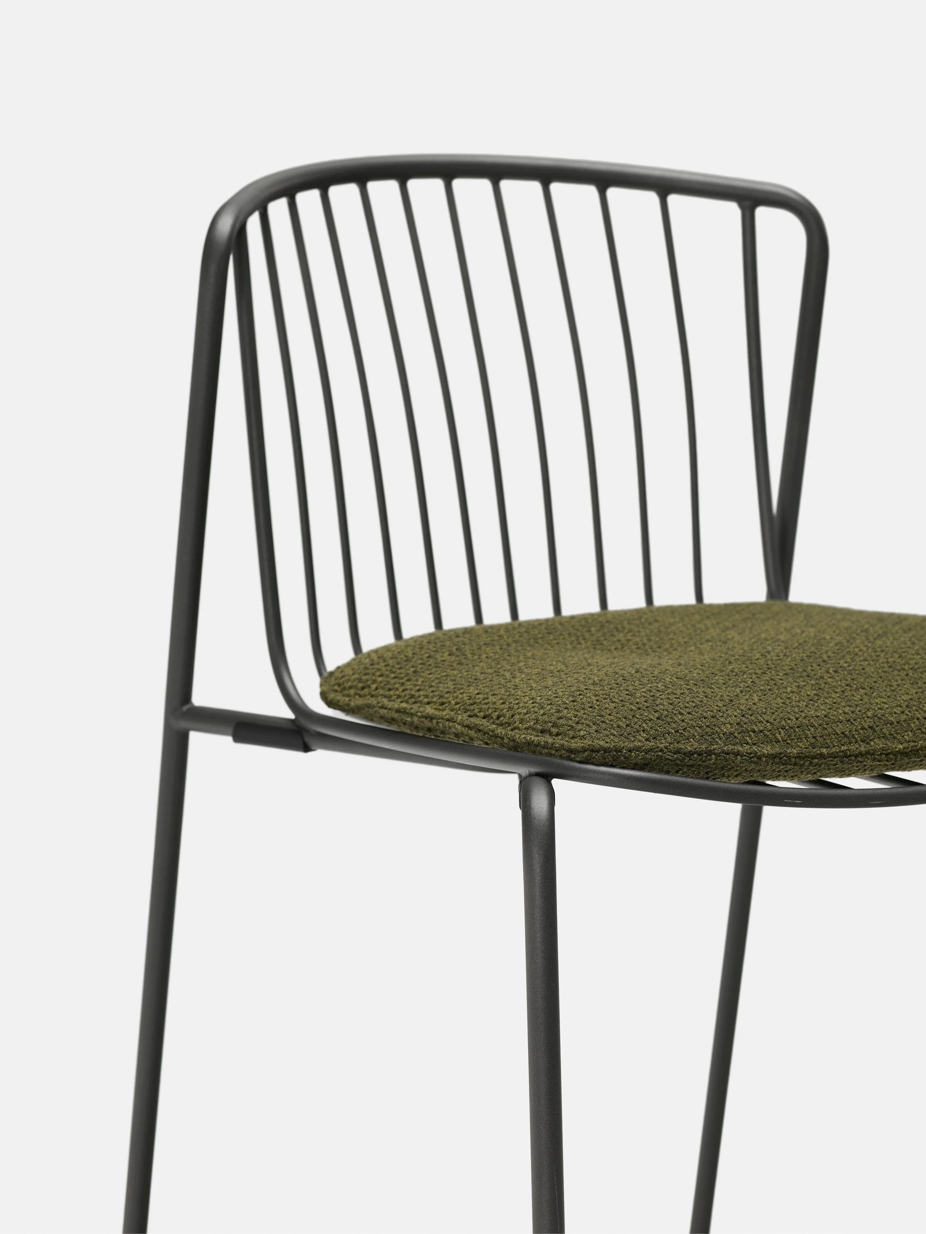 A modern chair with a minimalist black metal frame, a backrest made of vertical metal rods, and an olive green fabric seat cushion, shown against a plain white background.