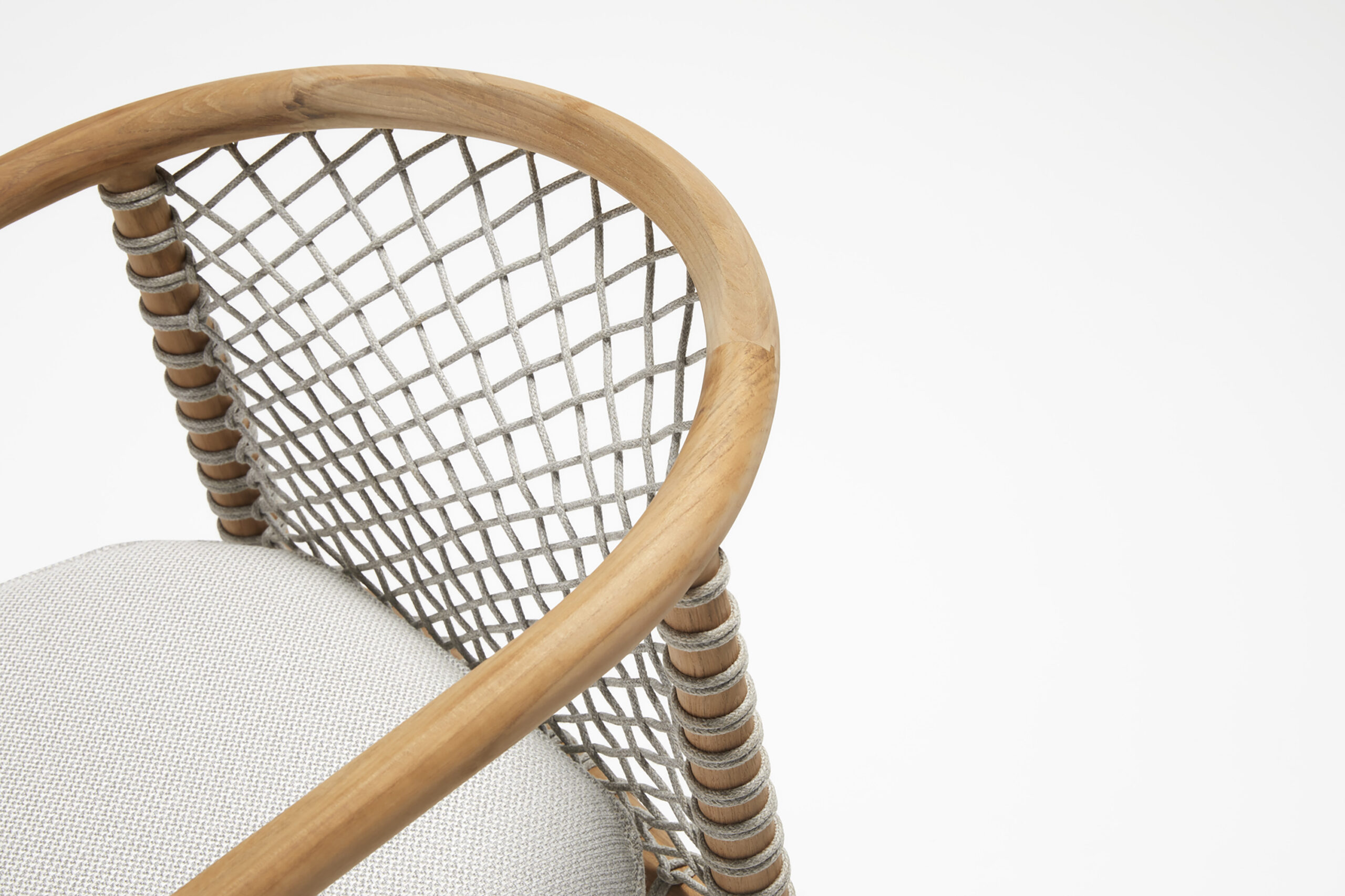 A close-up of a chair featuring a light wood frame with a curved backrest. The backrest is made of crisscrossed rope, and the seat is upholstered in light gray fabric. The design is modern and minimalist, with clean lines and natural materials.