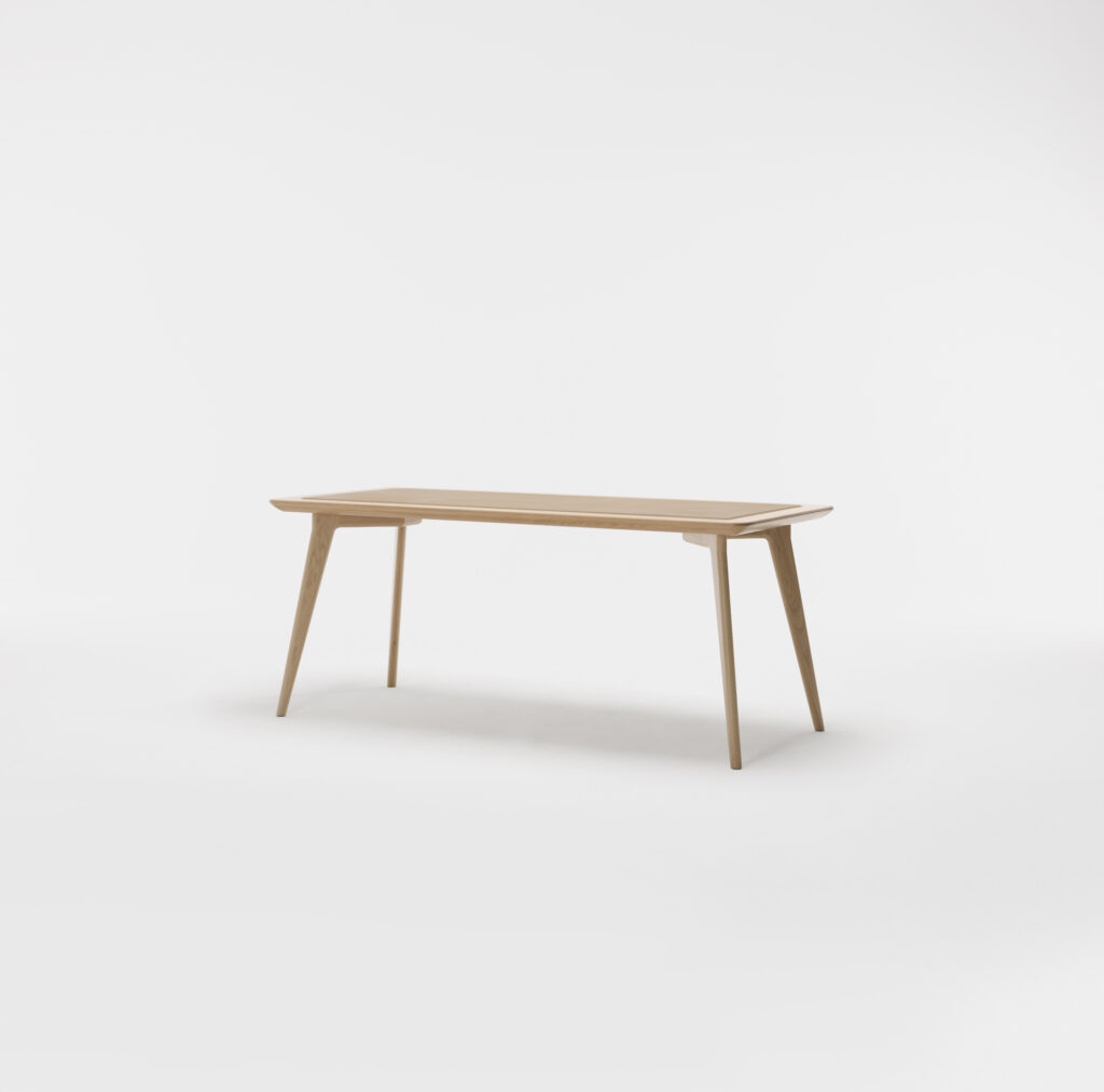 A minimalist wooden table with a rectangular top and four tapered legs. The design is sleek and modern with clean lines, and the natural wood finish gives it a light, airy appearance. The table is set against a plain white background.