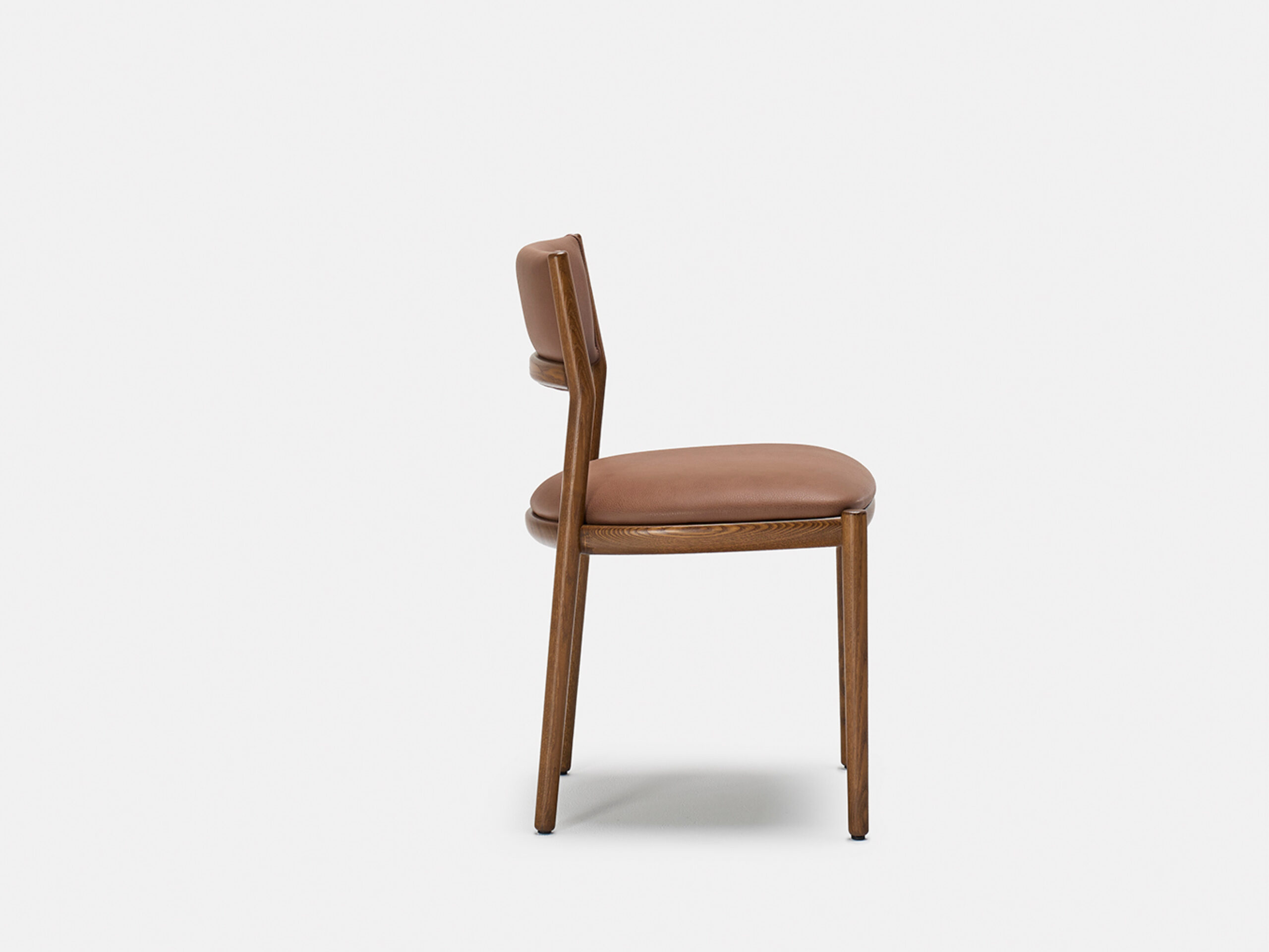 A wooden chair with light brown leather upholstery on the seat and backrest, shown from the side against a plain white background.
