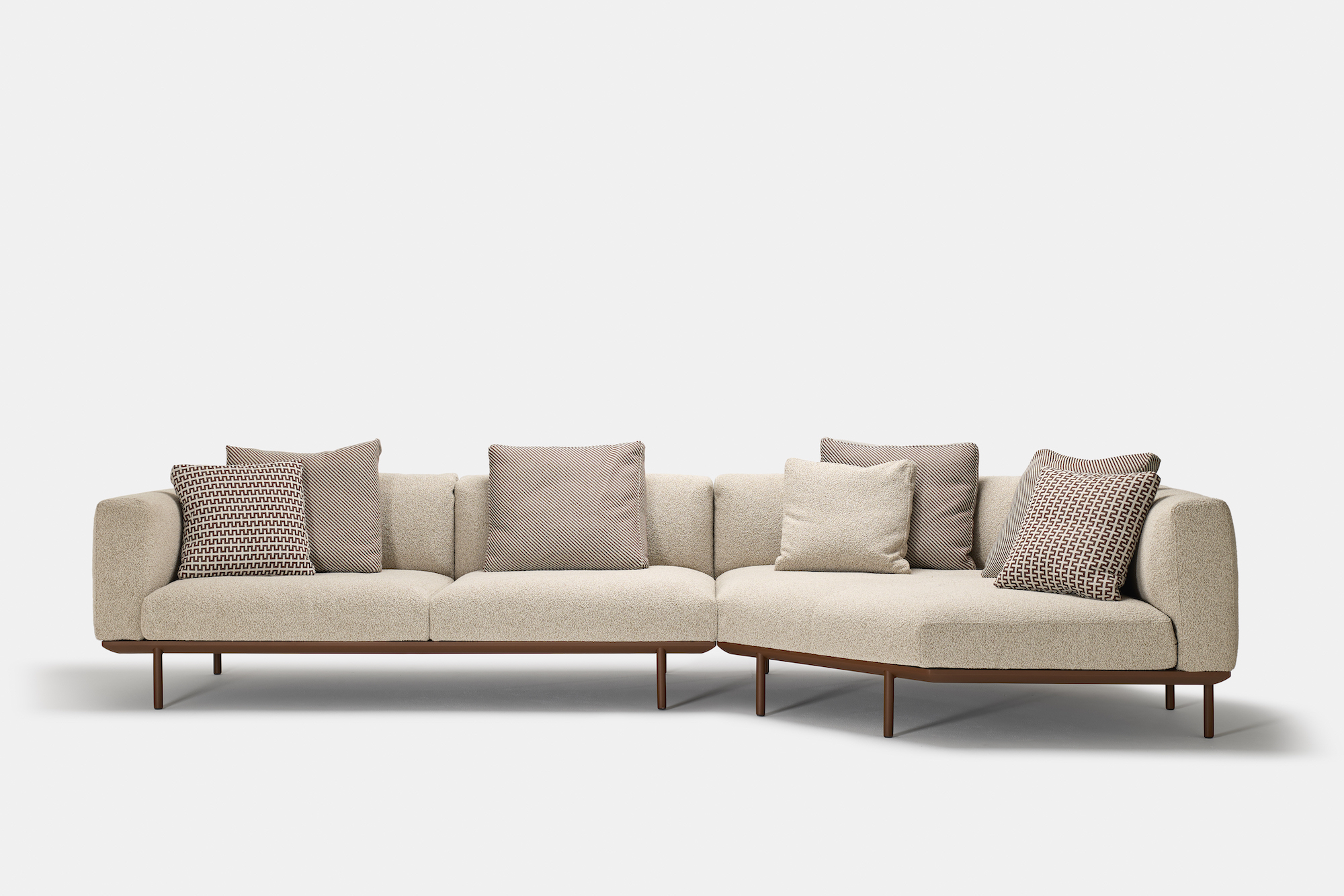 A modern, beige sectional sofa with a wooden base and legs, featuring seven assorted textured throw pillows in neutral tones, set against a plain white background.