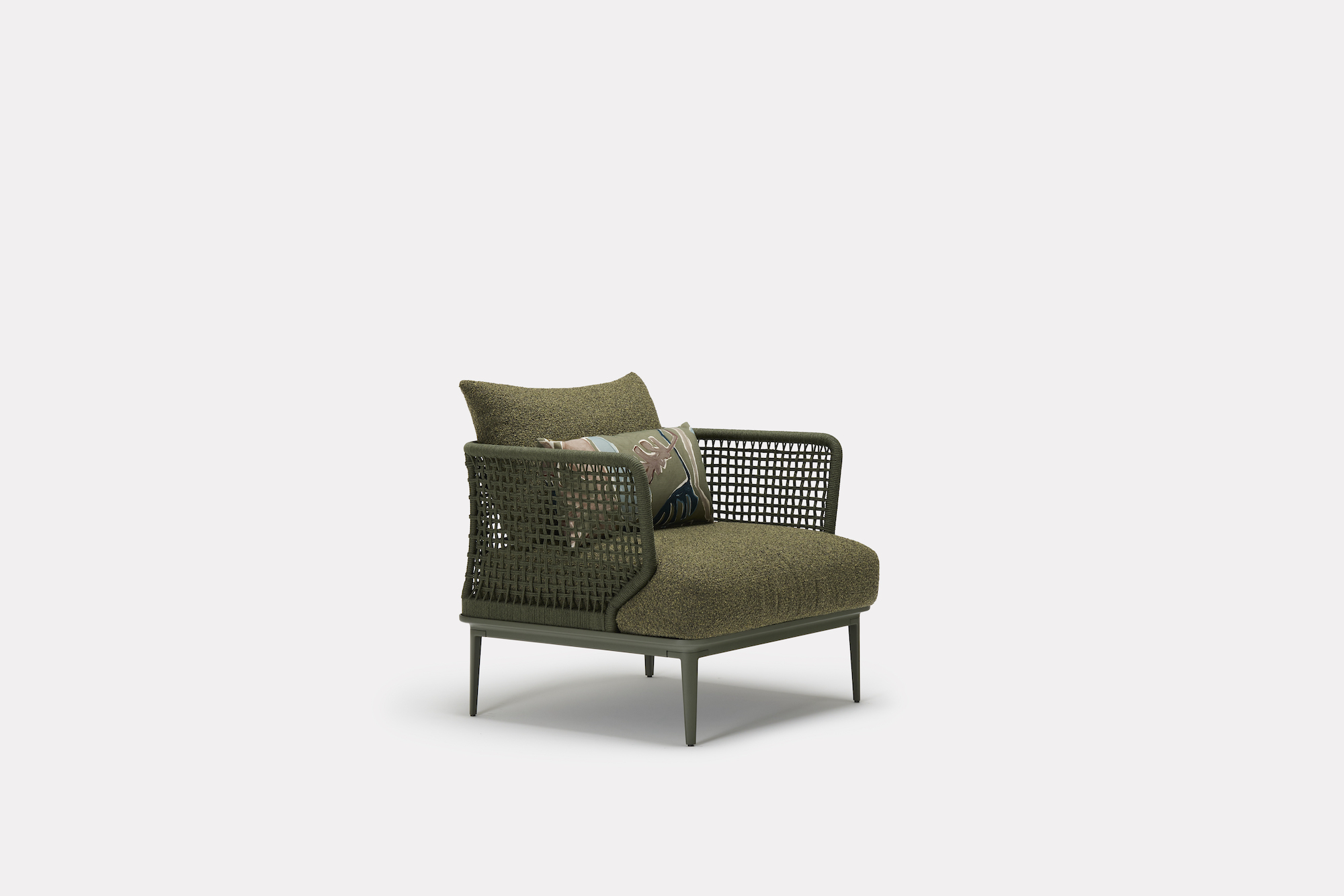 A modern armchair with an olive green cushion, woven sides, and a matching backrest. It features slim metal legs and includes a decorative pillow with a colorful pattern. The background is plain white.