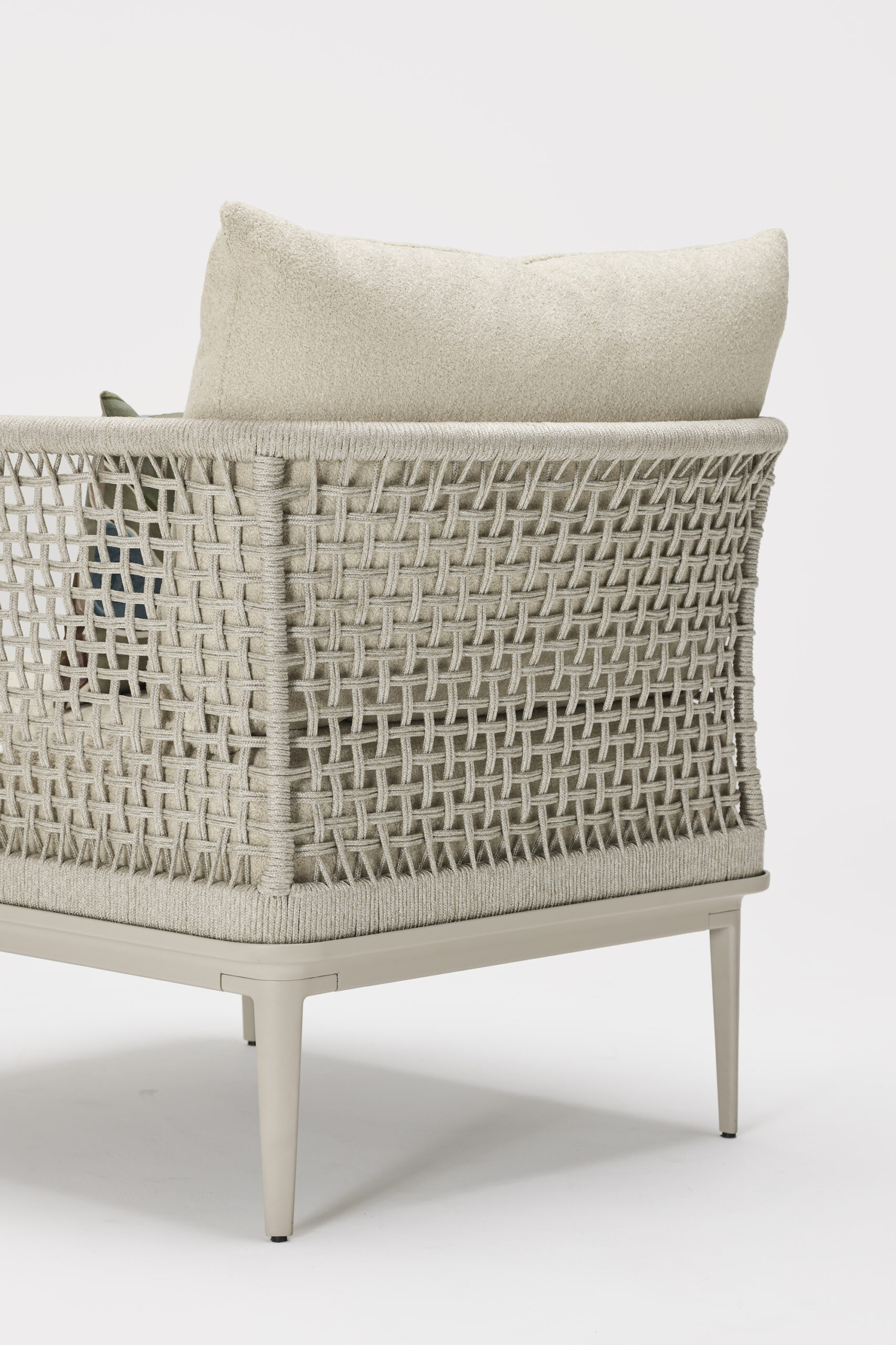 A stylish armchair with a woven beige frame, cushioned seat, and backrest, shown from a rear side angle against a plain white background.