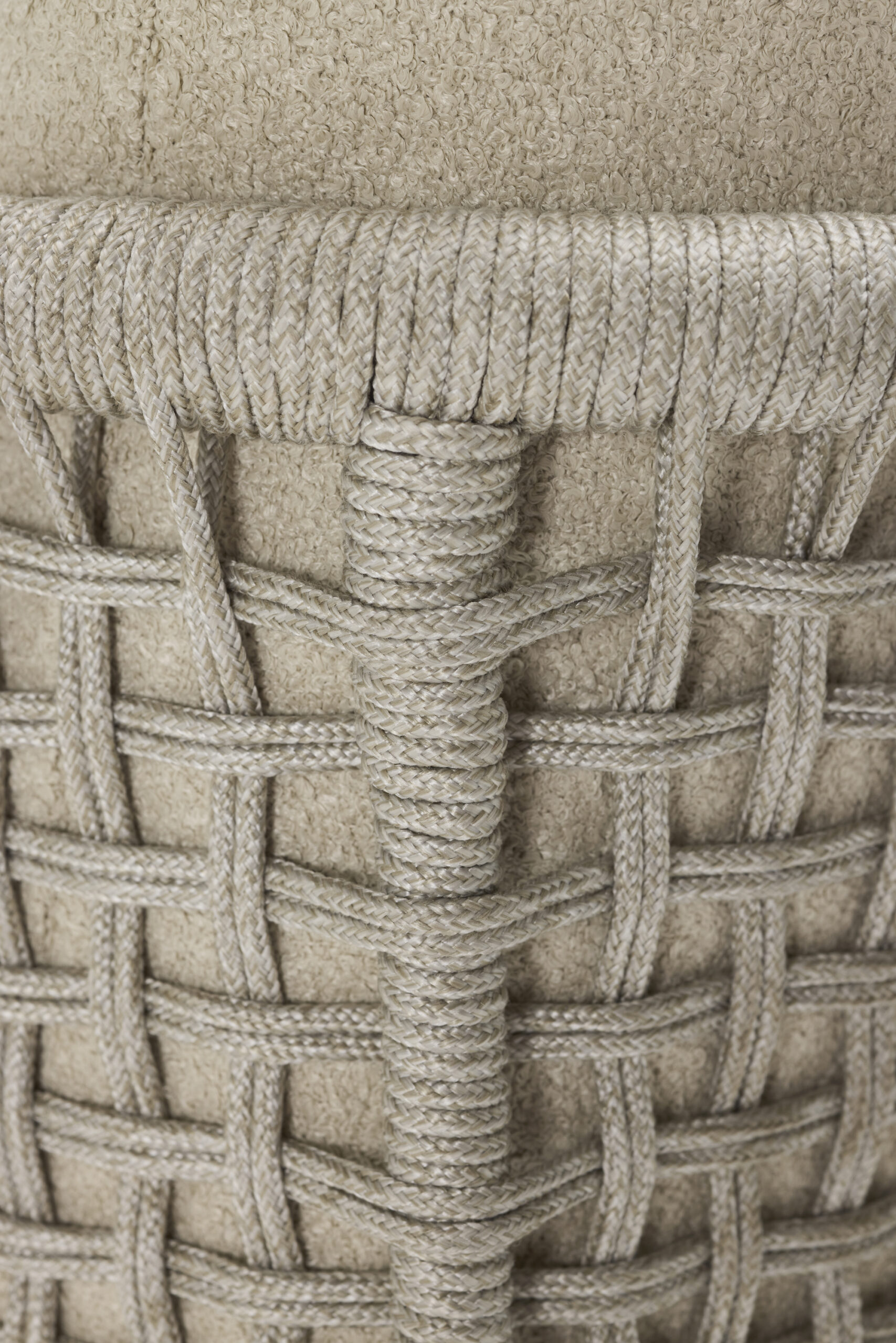 Close-up of beige woven rope forming a textured, grid-like pattern around a cylindrical, soft fabric surface. The craftsmanship and detail of the weaving technique are clearly visible.