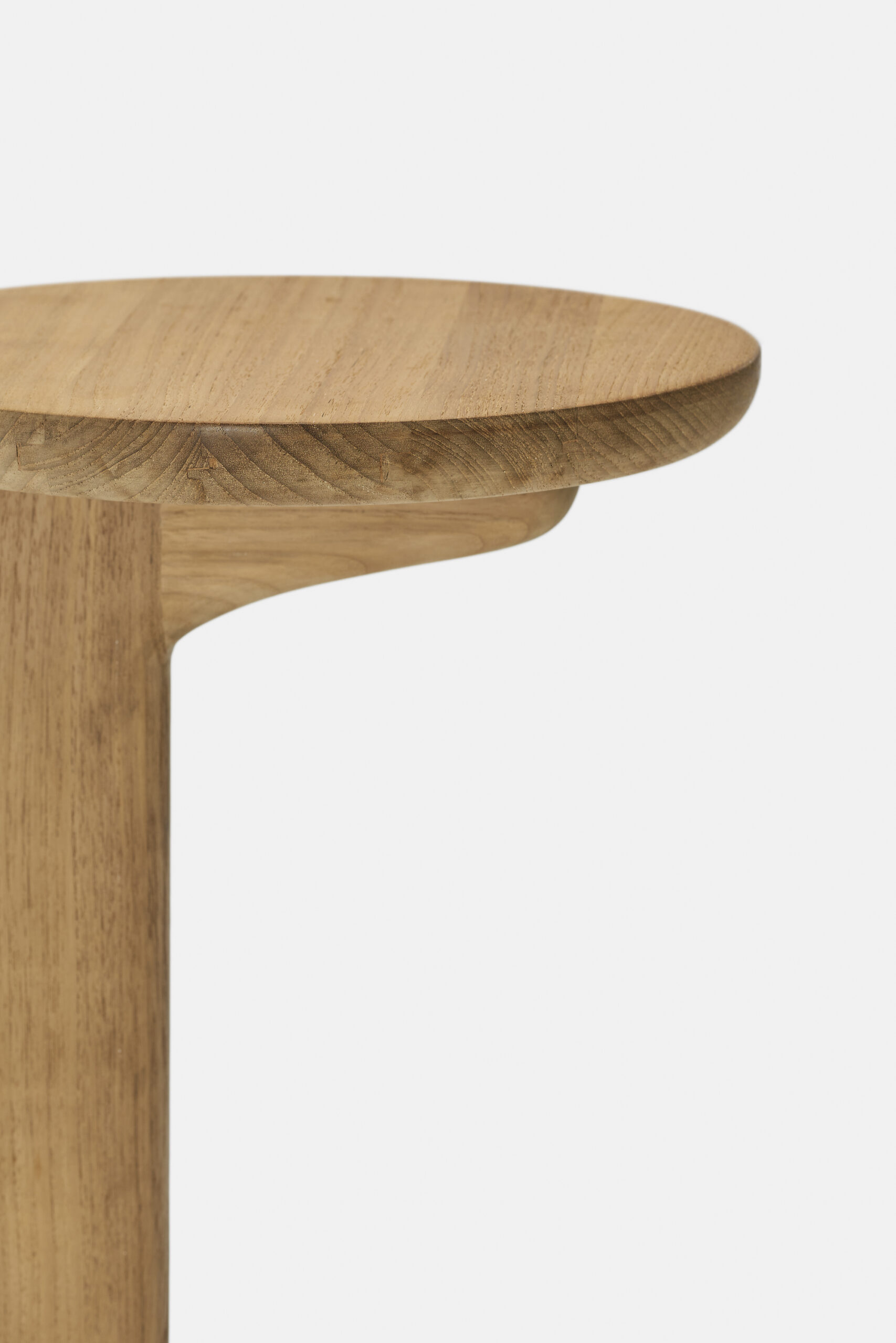 Close-up of a wooden table or stool with a smooth, rounded edge and a light natural finish, set against a plain white background.