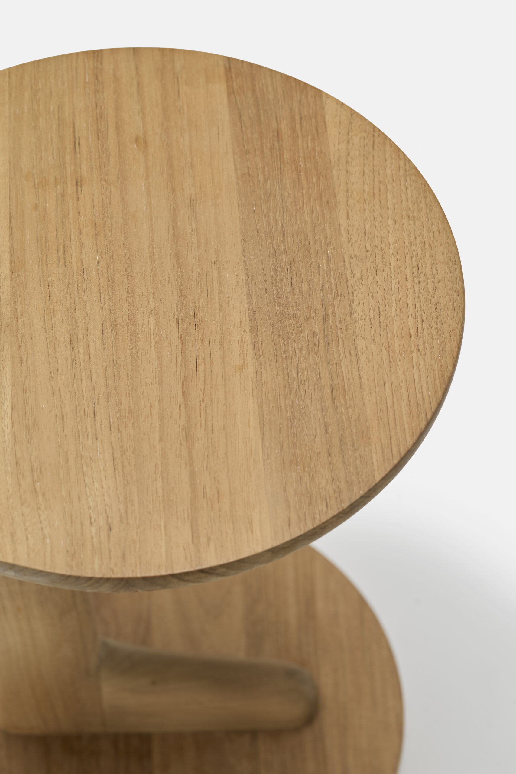 A close-up view of a round wooden table with a light natural finish, showing its smooth surface and wood grain pattern against a plain white background.