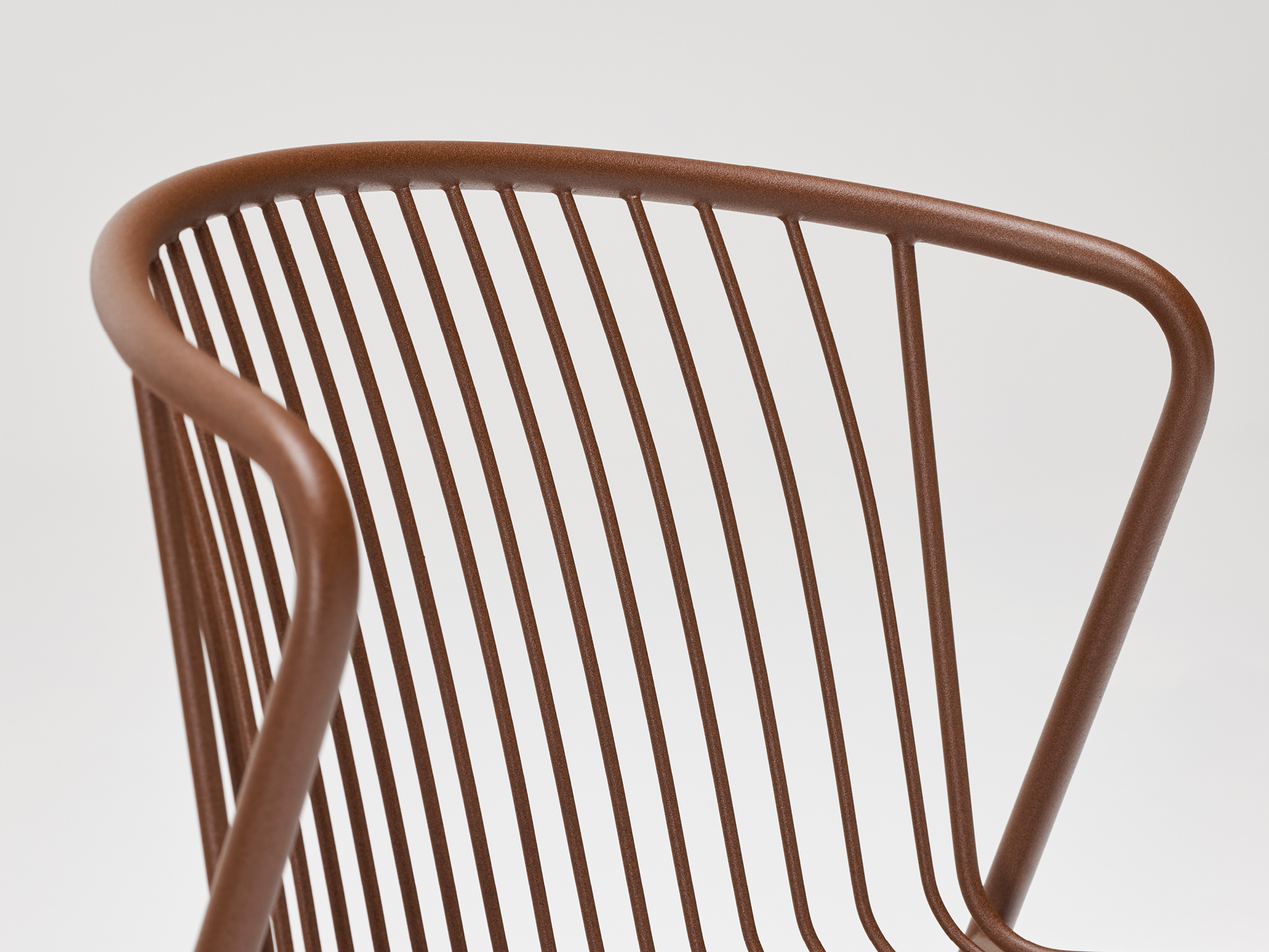 Close-up of a modern chair with a curved metal frame and evenly spaced vertical bars, finished in a matte brown color, set against a plain white background.