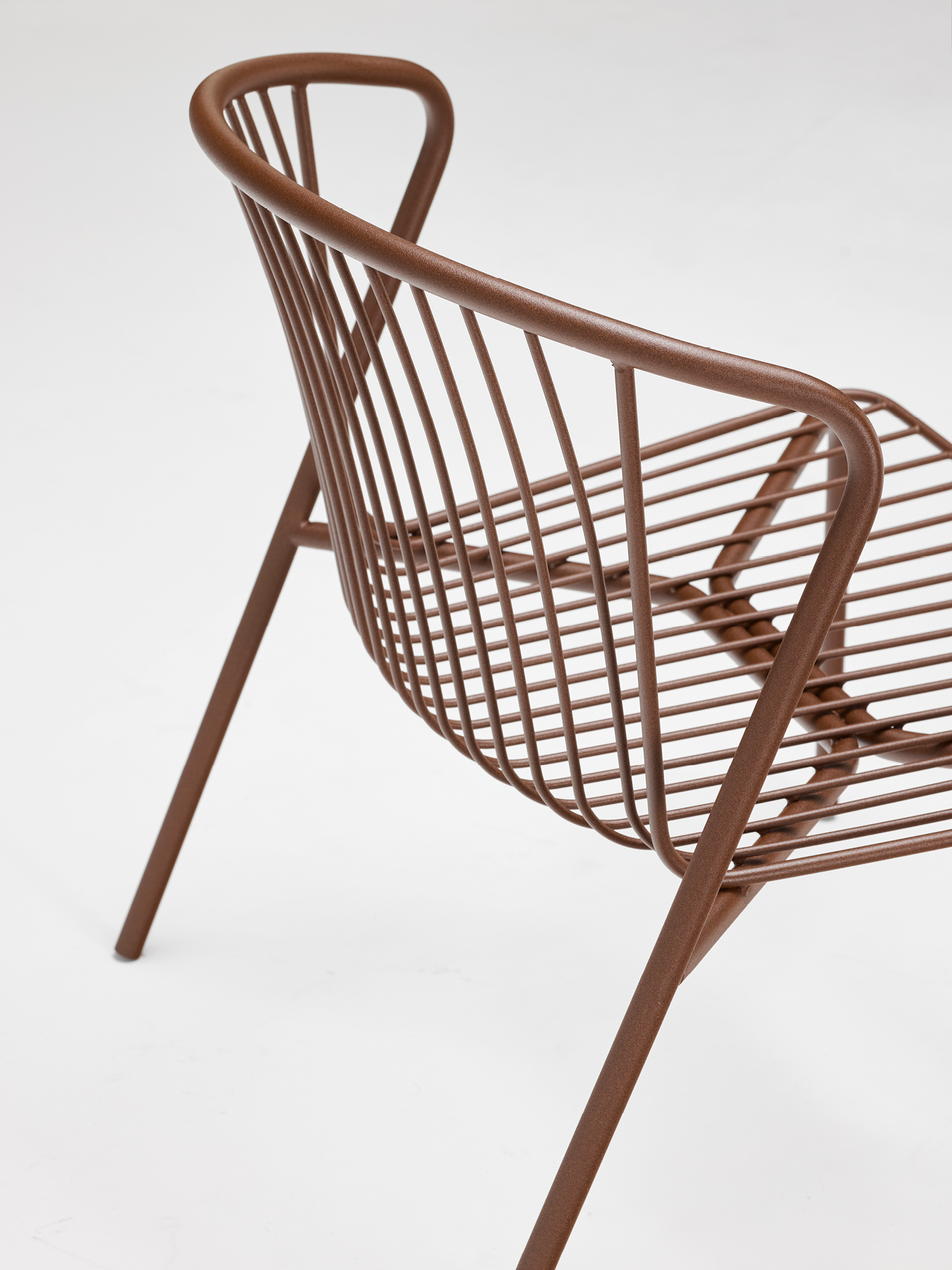 A modern chair made of brown metal rods, featuring a curved backrest and seat with a minimalist, open design, placed against a plain white background.